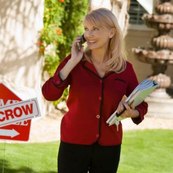 First Time Home Buyer Myths - Real Estate agent standing in front of a house in escrow sign.