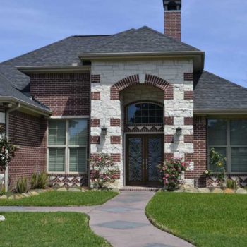 Green, curated lawn leading to front door behind two columns. - Real Estate San Marcos TX