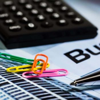 Colorful paperclips on paperwork beside calculator