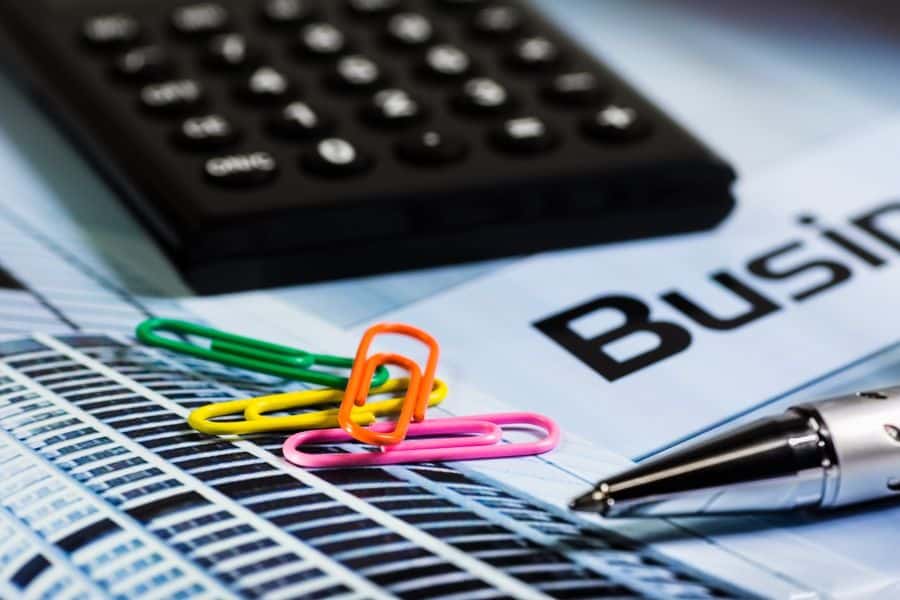 Colorful paperclips on paperwork beside calculator