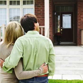 Happy couple in front of home