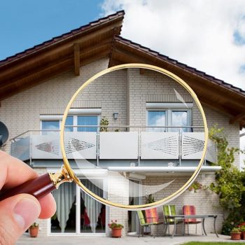 Man inspecting a house with magnifying glass