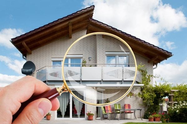 Man inspecting a house with magnifying glass