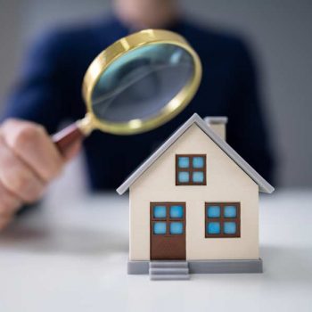 Magnifying glass held to a toy model of a house