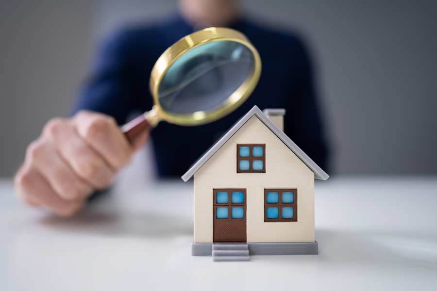 Magnifying glass held to a toy model of a house