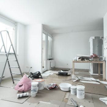 The inside of a home being renovated, with a ladder, paint, and miscellaneous items laying around.