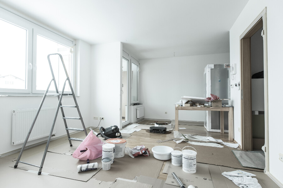 The inside of a home being renovated, with a ladder, paint, and miscellaneous items laying around.