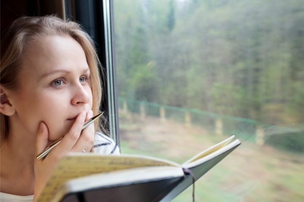 woman brainstorming while writing a letter in her journal