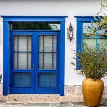 cool house with grecian blue door and container garden in the front